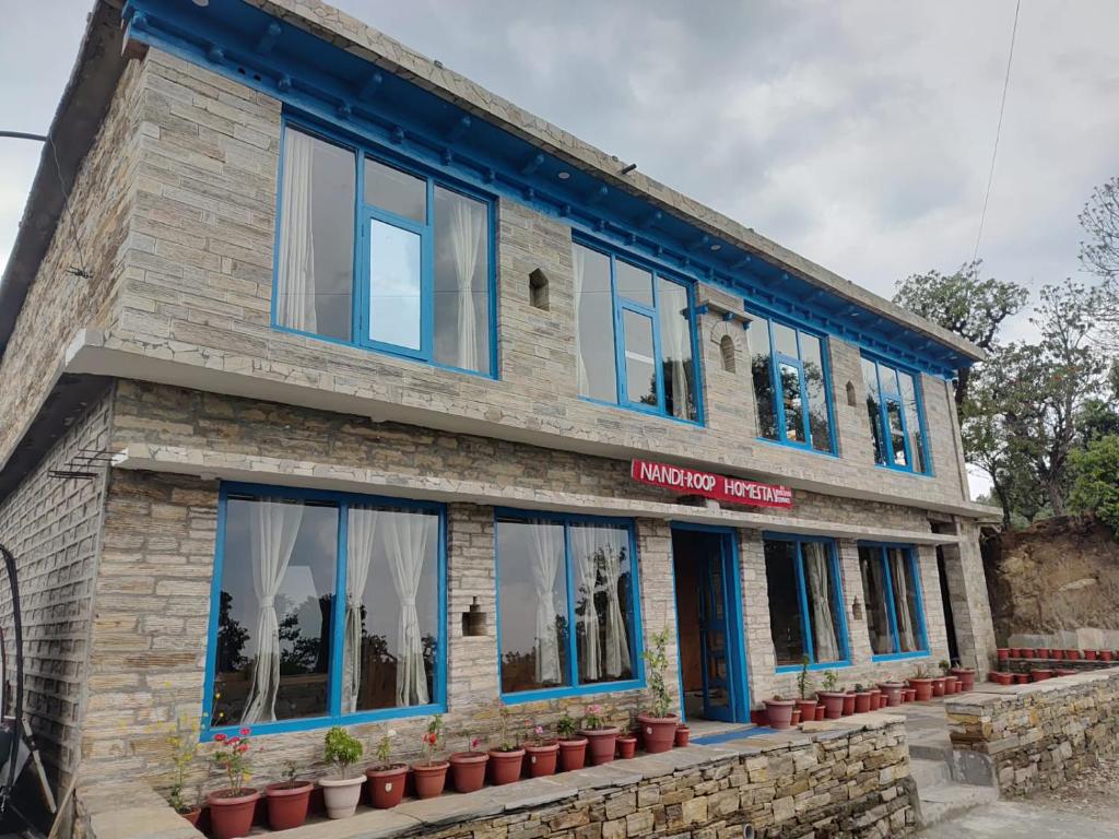 a building with blue windows and potted plants at Nandi Roop Homestay in Panuānaula