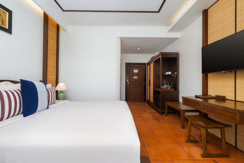 A bedroom view showing the bed, desk, TV and entry-side storage.