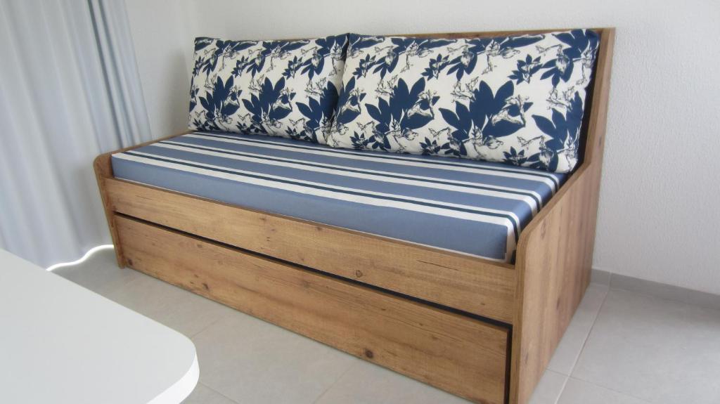 a bed with a blue and white pillow on it at Residencial Marbella in Bombinhas