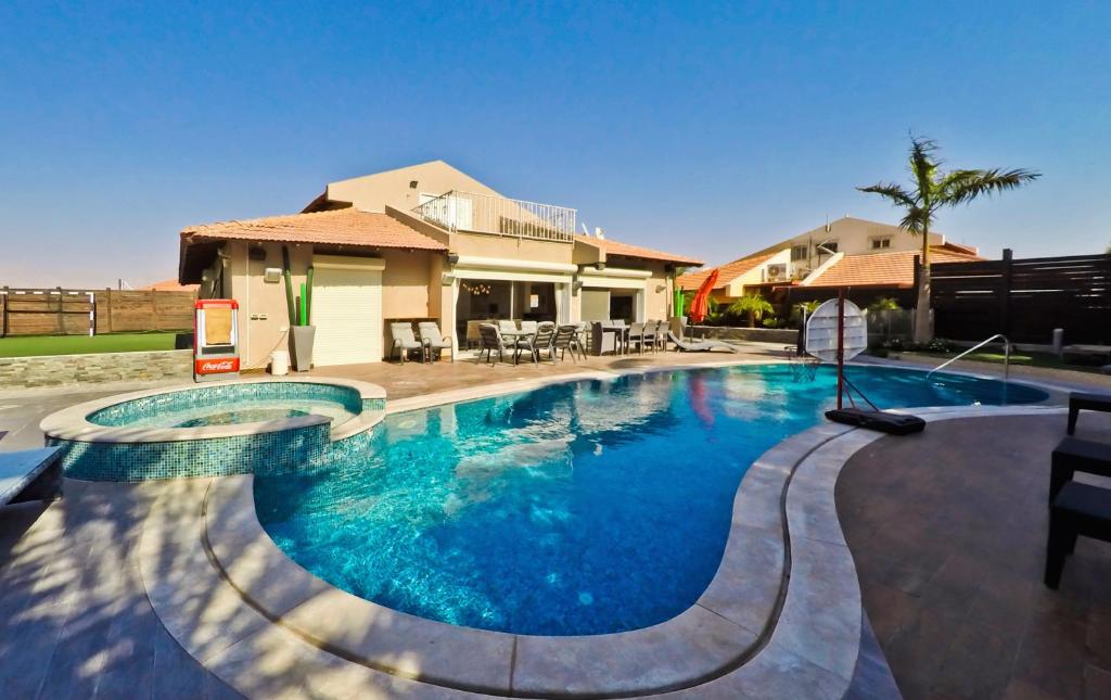 a swimming pool in front of a house at Villa Riviera Eilat in Eilat