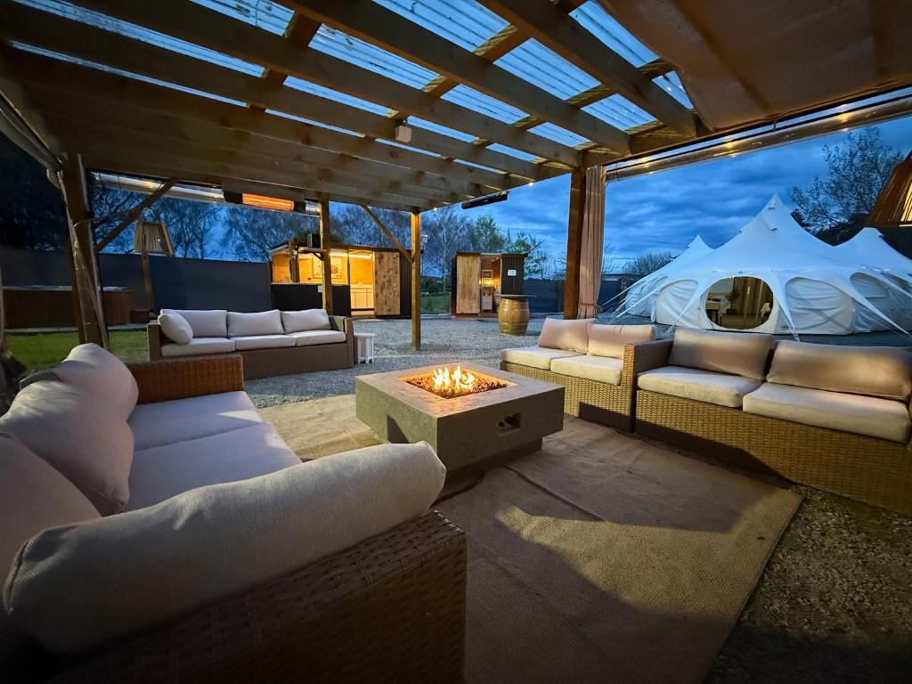 a patio with couches and a fire pit at Forest Hillside Glamping Retreat in Lochiel