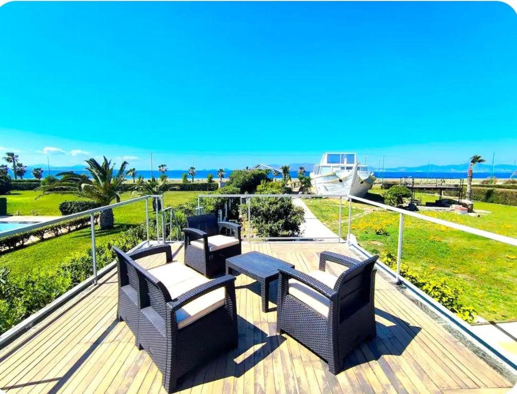 a deck with chairs and tables and the ocean at Psalidi beach house in Psalidi