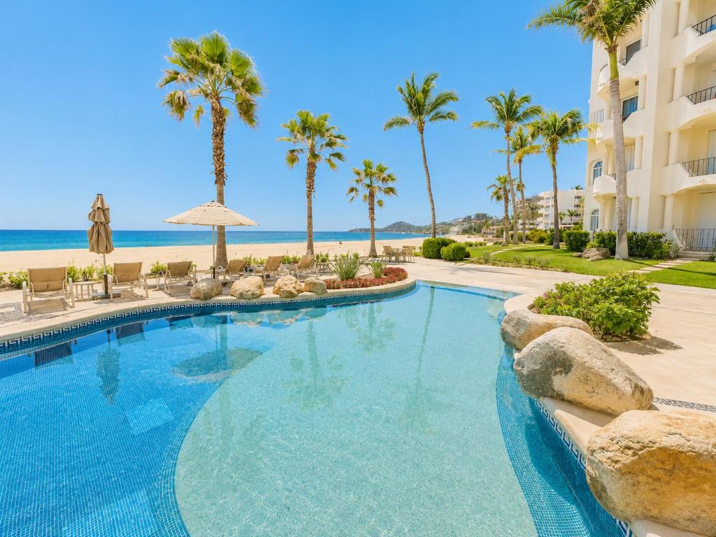 a swimming pool with palm trees and a beach at Mykonos Recently remodeled 1BR Beach Escape great view! in San José del Cabo