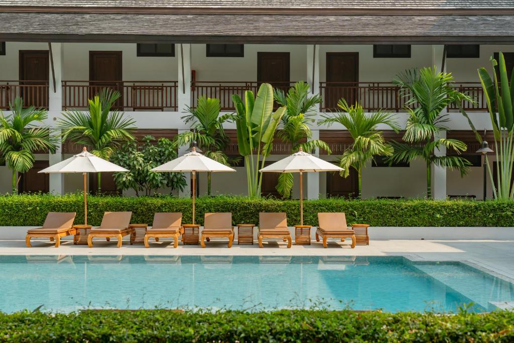 A broad view across the pool to shaded loungers and guest-room balconies.