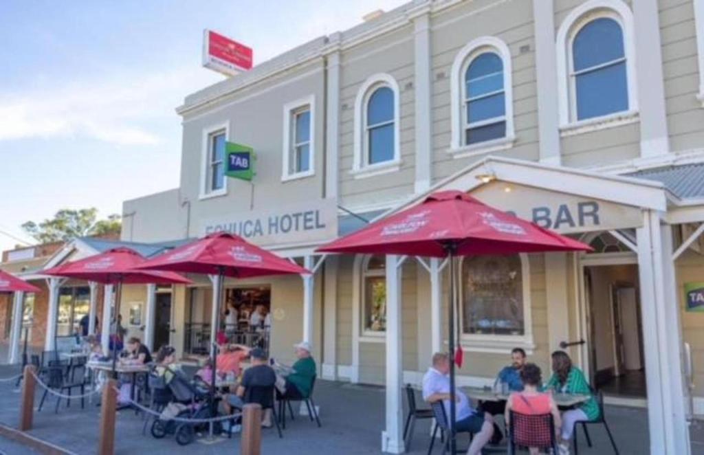 Eine Gruppe von Menschen sitzt an Tischen vor einer Bar. in der Unterkunft Echuca Hotel in Echuca