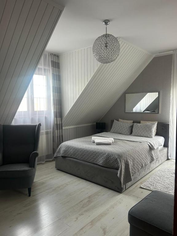 a bedroom with a bed and a chair at Gościniec Pod Lipą in Mikołajki