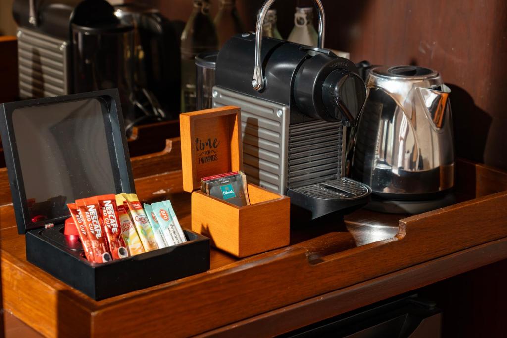 A wooden beverage station holds a coffee machine, kettle and assorted drinks.