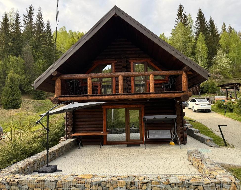 a log cabin with a porch and a balcony at Zrub House Карпати in Rozhanka Nizhnyaya