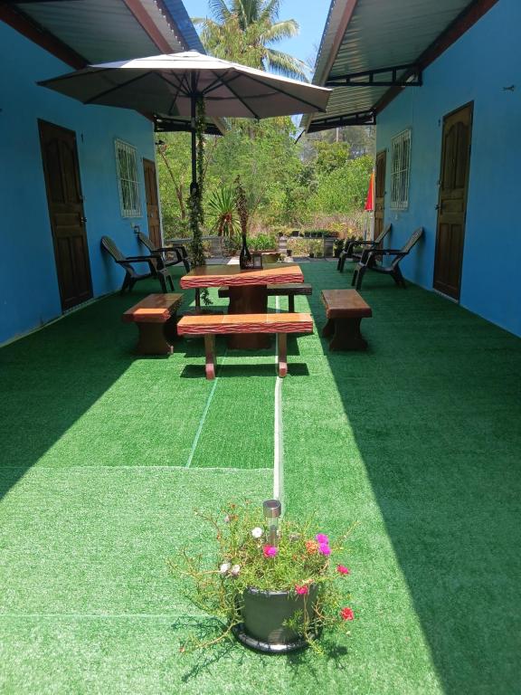 a patio with a picnic table and some flowers at Baan KaemSai in Khao Lak