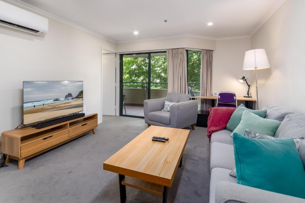 a living room with a couch and a tv at Central 2-bed Apartment with Gym and Spa in Canberra