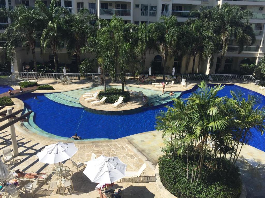 a large swimming pool with palm trees and umbrellas at Le Parc Residential Resort in Rio de Janeiro