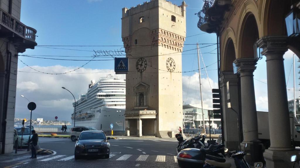 una torre dell'orologio su una strada cittadina con auto e moto di Piazzetta dei Consoli Apartment a Savona