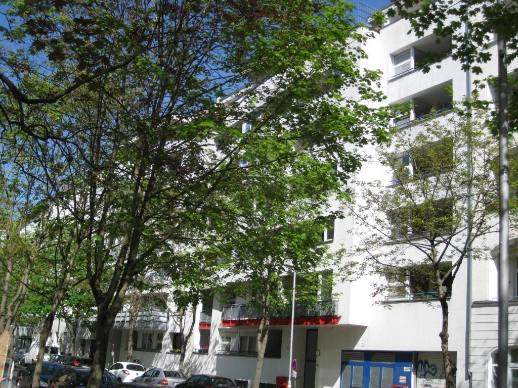ein weißes Gebäude mit Bäumen davor in der Unterkunft Ferienwohnungen Familie Böckmann in Berlin