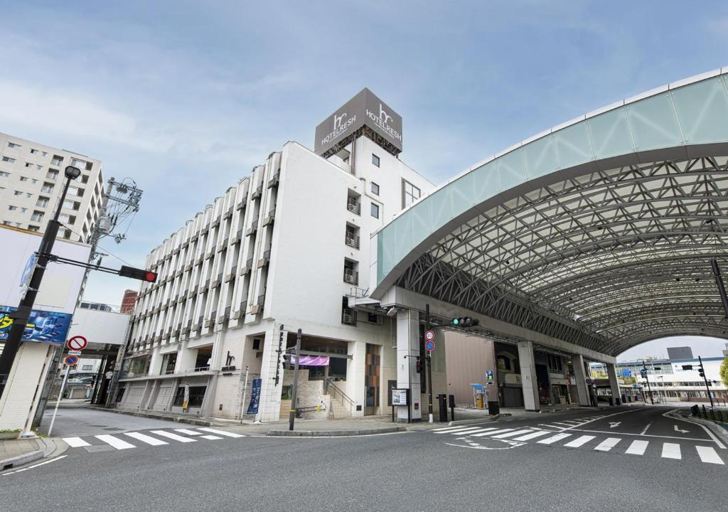 a large white building with a glass roof on a street at Hotel Resh Tottori Ekimae in Tottori