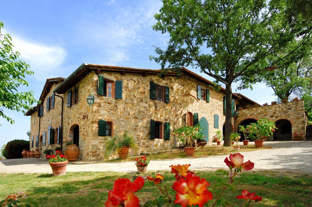 um edifício de pedra com flores em frente em Casa Vacanze Podere Casacce em San Casciano in Val di Pesa