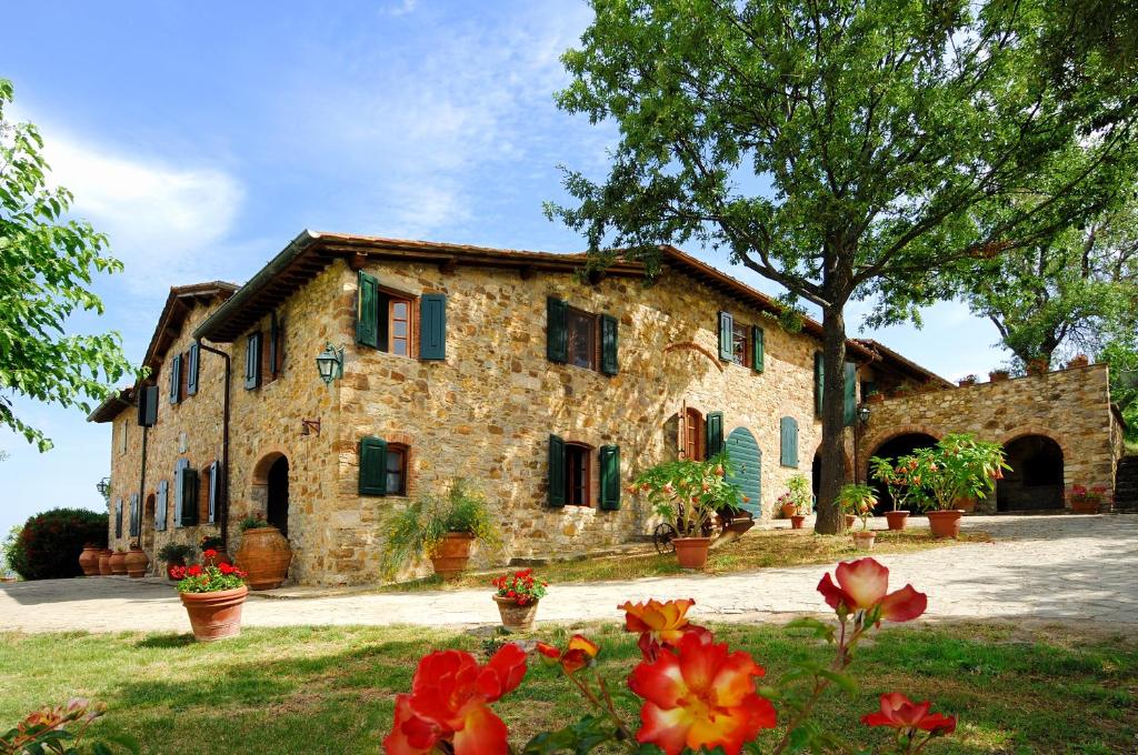 a stone building with flowers in front of it at Casa Vacanze Podere Casacce in San Casciano in Val di Pesa