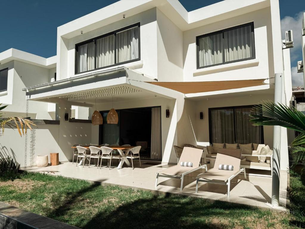 a white house with chairs and a table at North Island View Family Duplex with private pool by LOV Mauritius in Grande Gaube