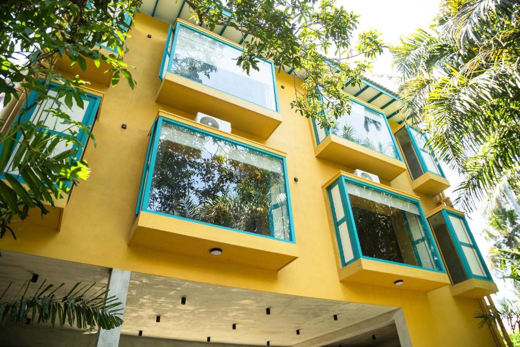 a yellow building with blue windows on it at KAHA by TONIK, Talpe - Pool & Garden in Talpe