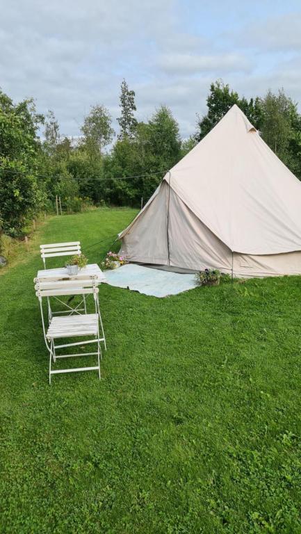 a tent with two chairs and a table in the grass at Glampingtält in Österbybruk