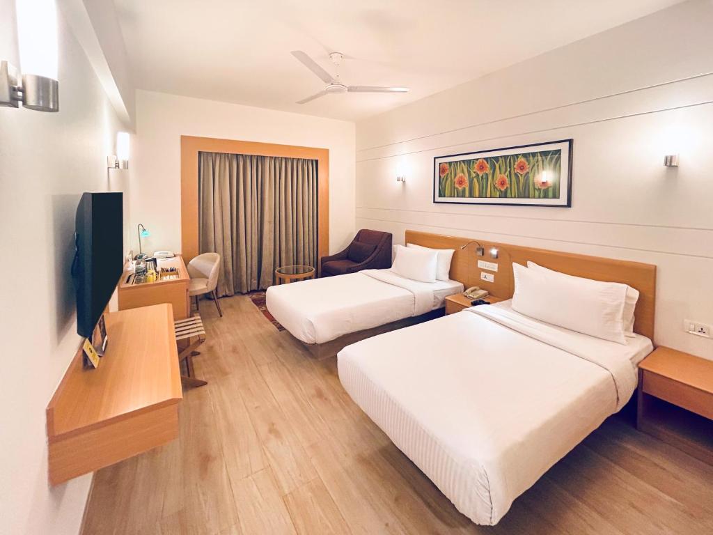 a hotel room with two beds and a television at Lemon Tree Hotel, Gachibowli, Hyderabad in Hyderabad
