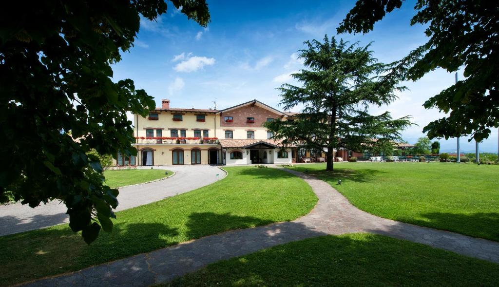 een groot gebouw met een boom in het midden van een veld bij Relais Picaron in San Daniele del Friuli