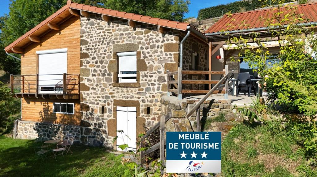 a small stone house with a sign in front of it at La maison vigneronne in Polignac