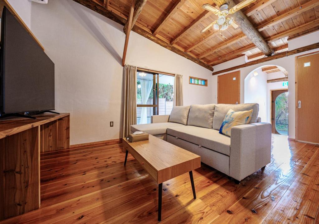 a living room with a couch and a tv at simAsim Cottage Kouri in Nakijin