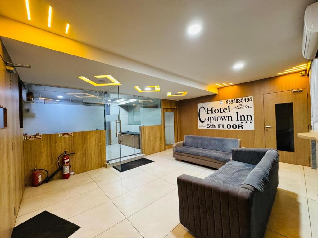 a living room with a couch and a sign on the wall at Hotel Captown Inn in Ahmedabad