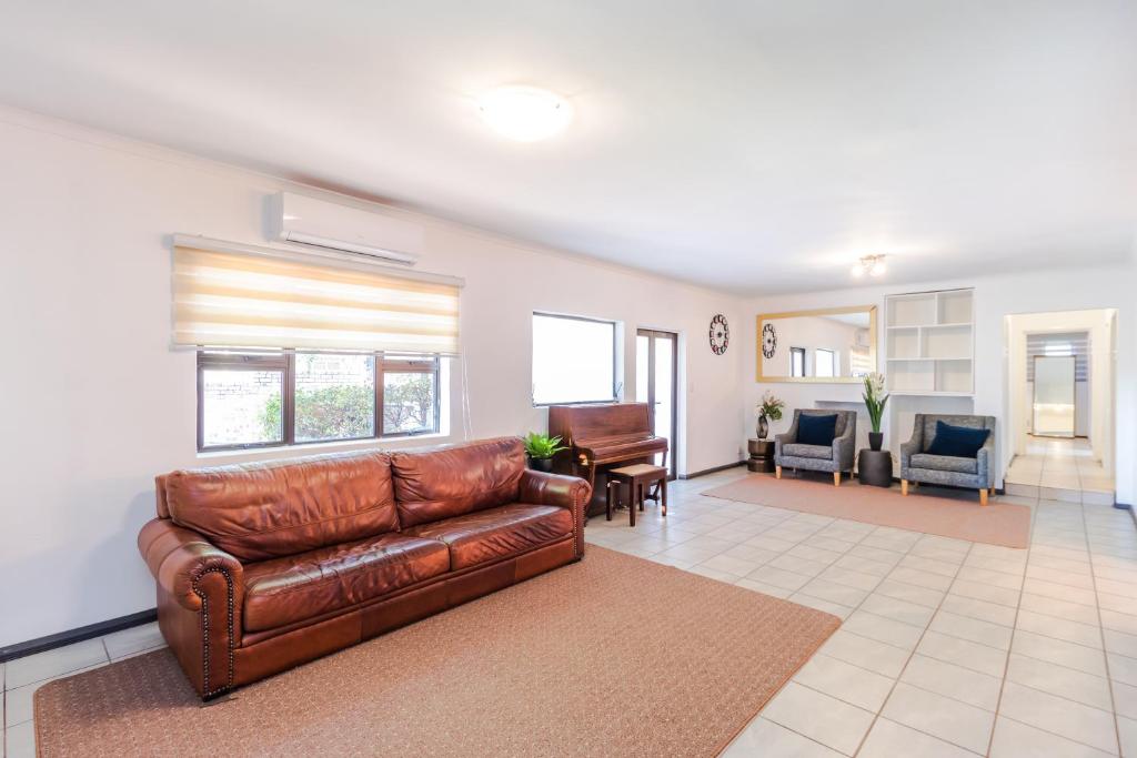 a living room with a brown leather couch at Urban Escapes - LINDEN COTTAGE in Johannesburg