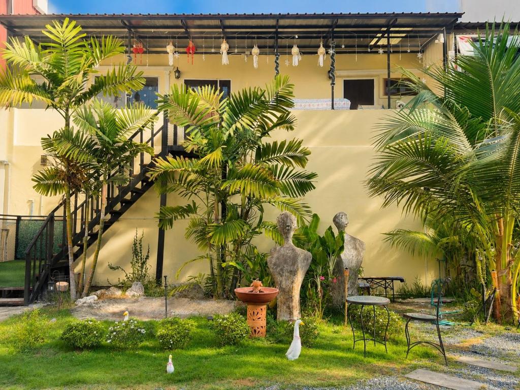 a garden with two statues and palm trees at inghome & guesthouse in Chiang Mai