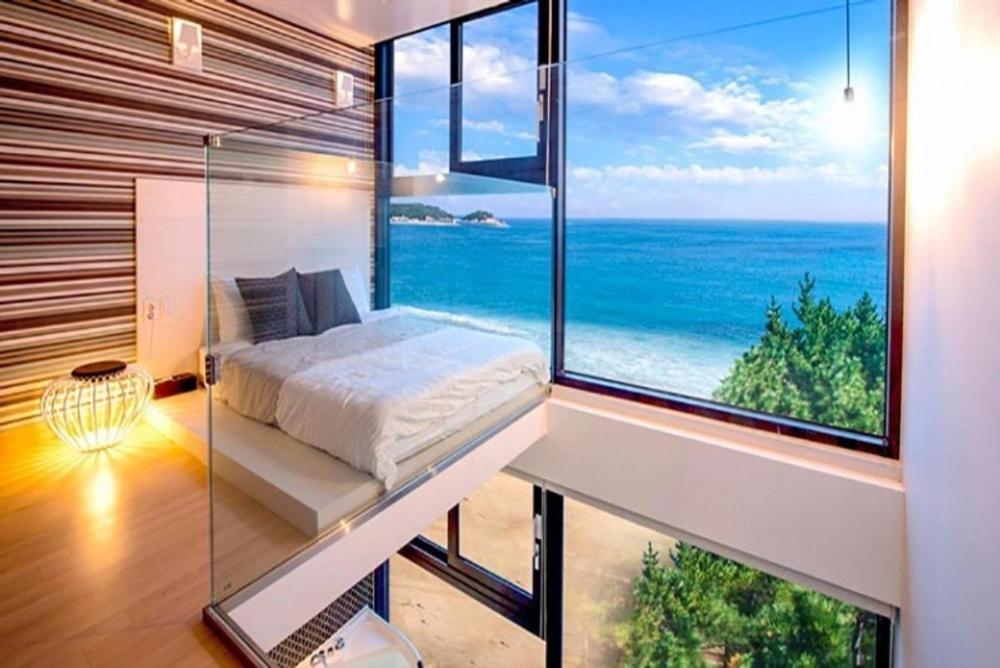 a bedroom with a bed and a large window with the ocean at Gosung La Henne Pull Villa J in Goseong