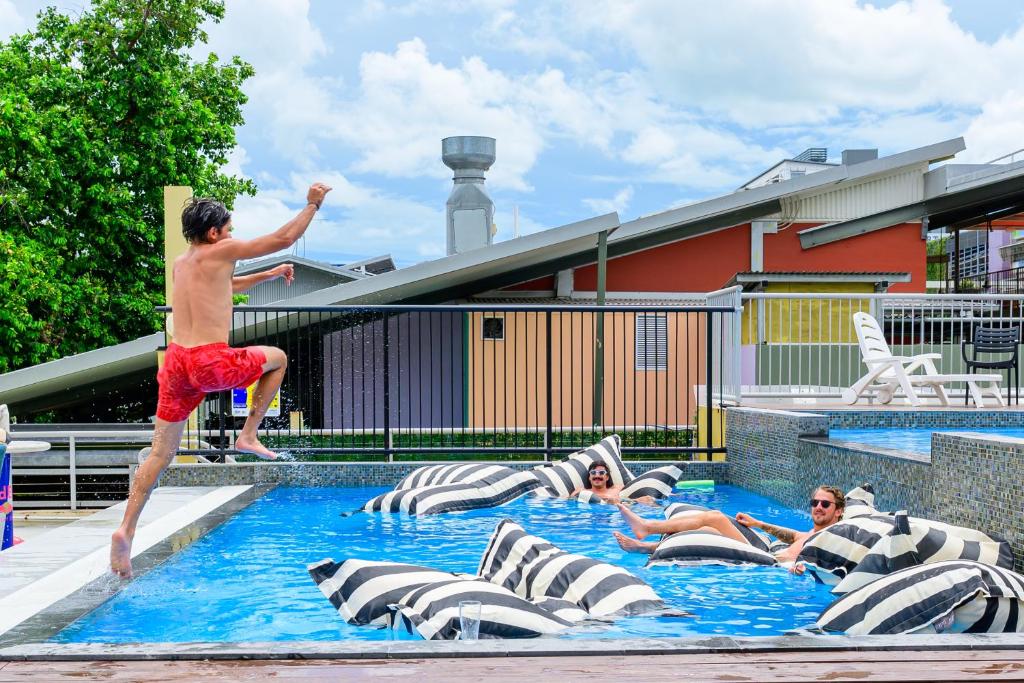 a man jumping into a swimming pool with people in it at MOM Darwin in Darwin