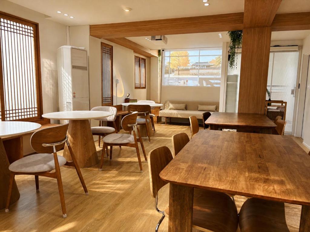 a room with tables and chairs and a couch at Moonraejung Hostel in Seoul