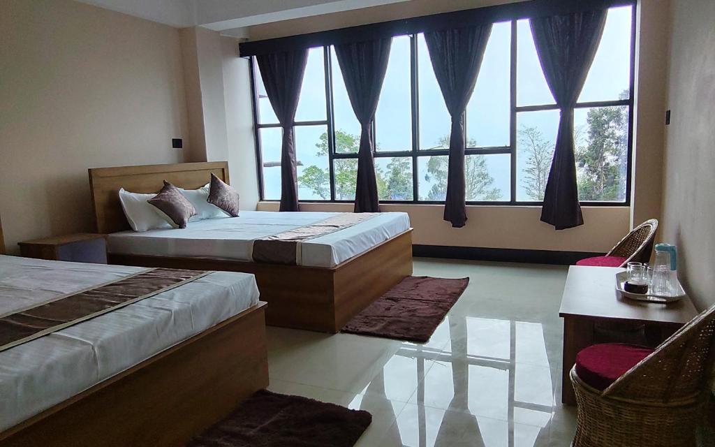 a bedroom with two beds and a large window at Marigold in Kalimpong