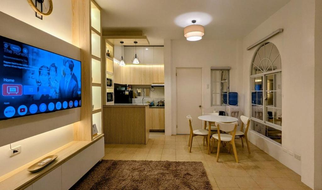 a living room with a table and a tv on a wall at Cityloft Bungalow in Dauis
