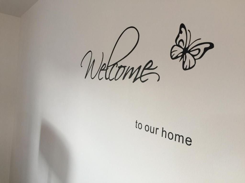 un papillon sur un mur avec les mots de bienvenue chez nous dans l'établissement Appartement near Disneyland, à Serris