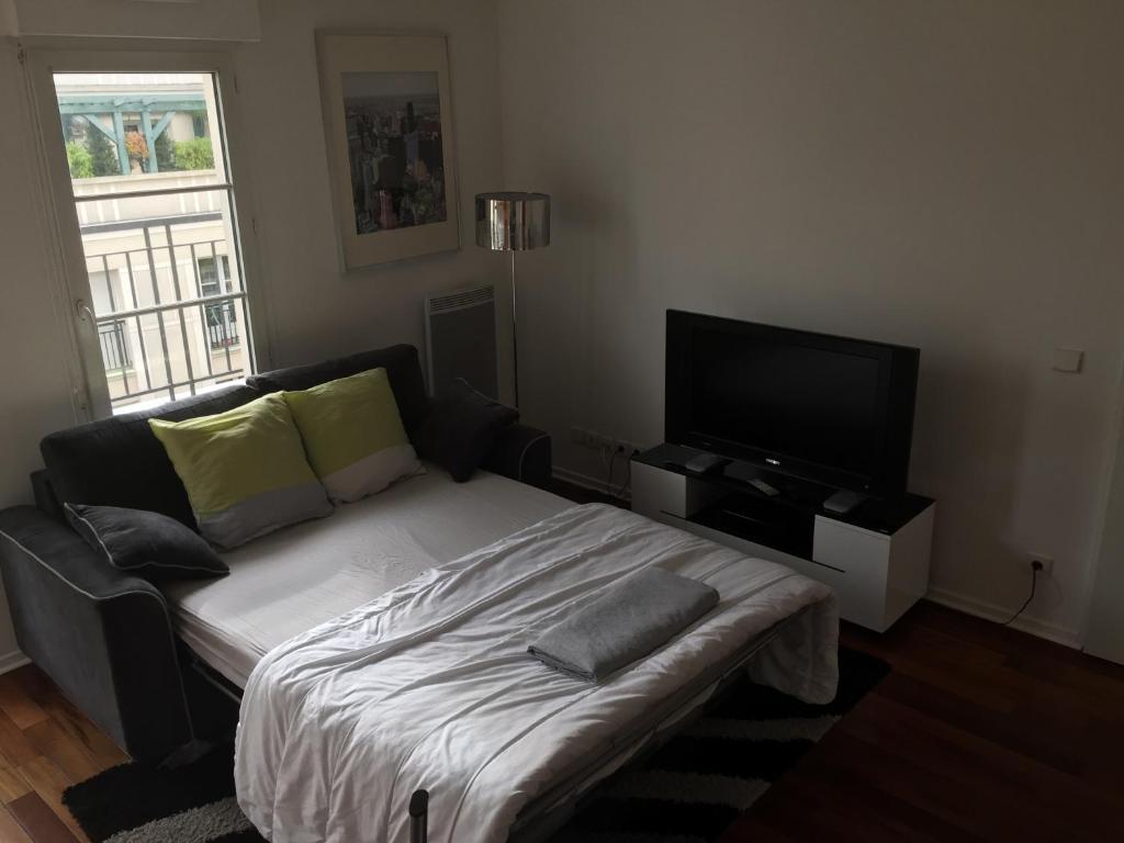 a bedroom with a bed and a flat screen tv at Appartement near Disneyland in Serris