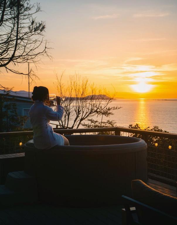 a woman taking a picture of the sunset at Private Blufftop Oceanview Hot Tub Fire Pit in Port Angeles
