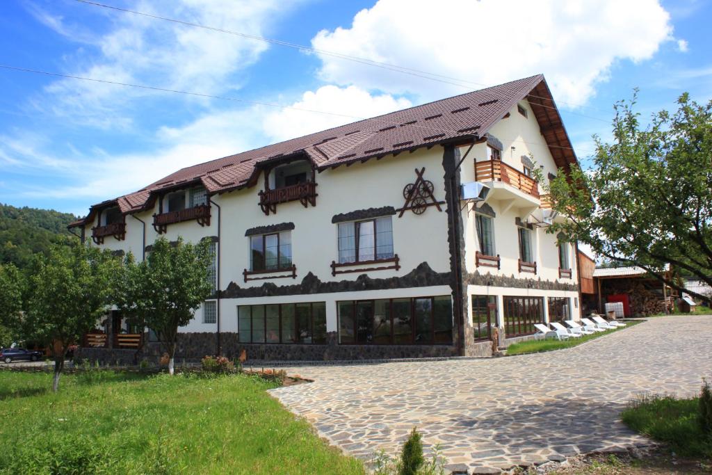 un gran edificio blanco con techo de gambrel en Pensiunea Lacramioara, en Săcel