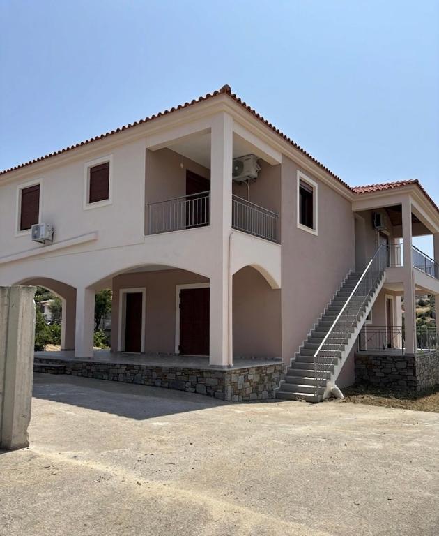a large white house with stairs in front of it at Βίλα Αντί Ονείρου-Διαμέρισμα Αριάδνη in Kriezá