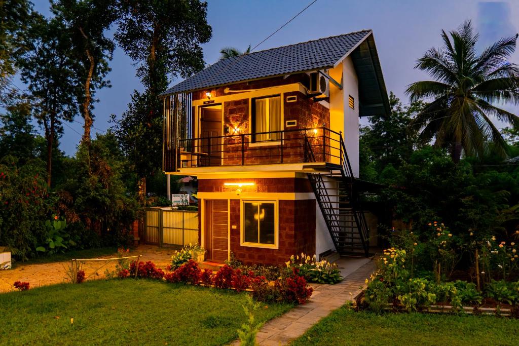 a house with a balcony and a yard at Avocado Cottages by Alaya Stays, Coorg in Suntikoppa