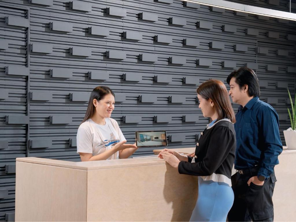A minimalist reception desk where guests are being assisted by a staff member.