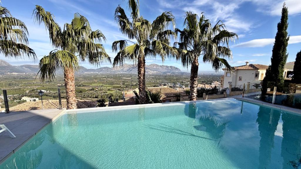a swimming pool with palm trees and mountains in the background at Villa Titulabo in Orba