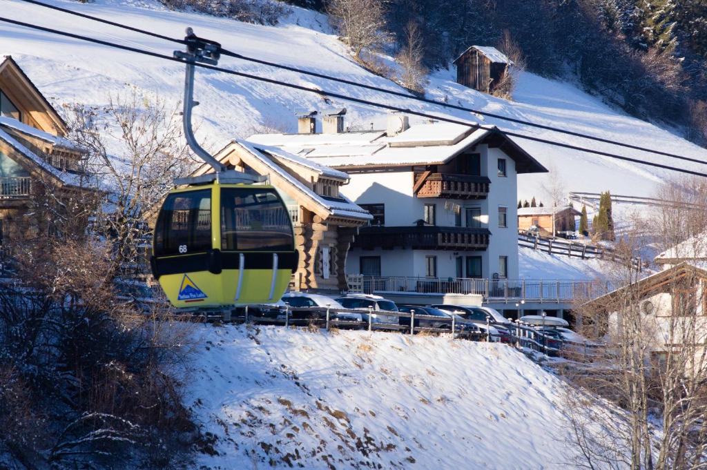 a yellow train traveling past a house in the snow at wolf.tirol in Ladis