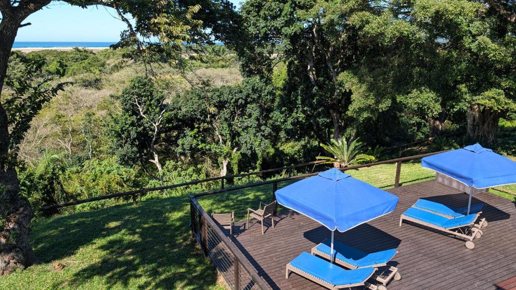 two blue umbrellas and lounge chairs on a deck at Ocean View Nature Lodge in St Lucia