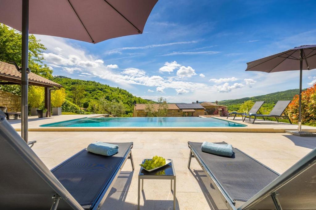 a swimming pool with two lounge chairs and an umbrella at Villa Palazza in Pazin