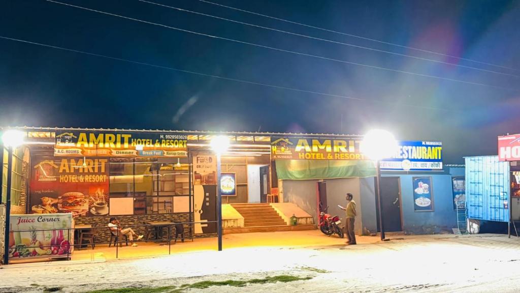 a man standing in front of a building at night at Amrit hotel & resort in Nārāyanpur