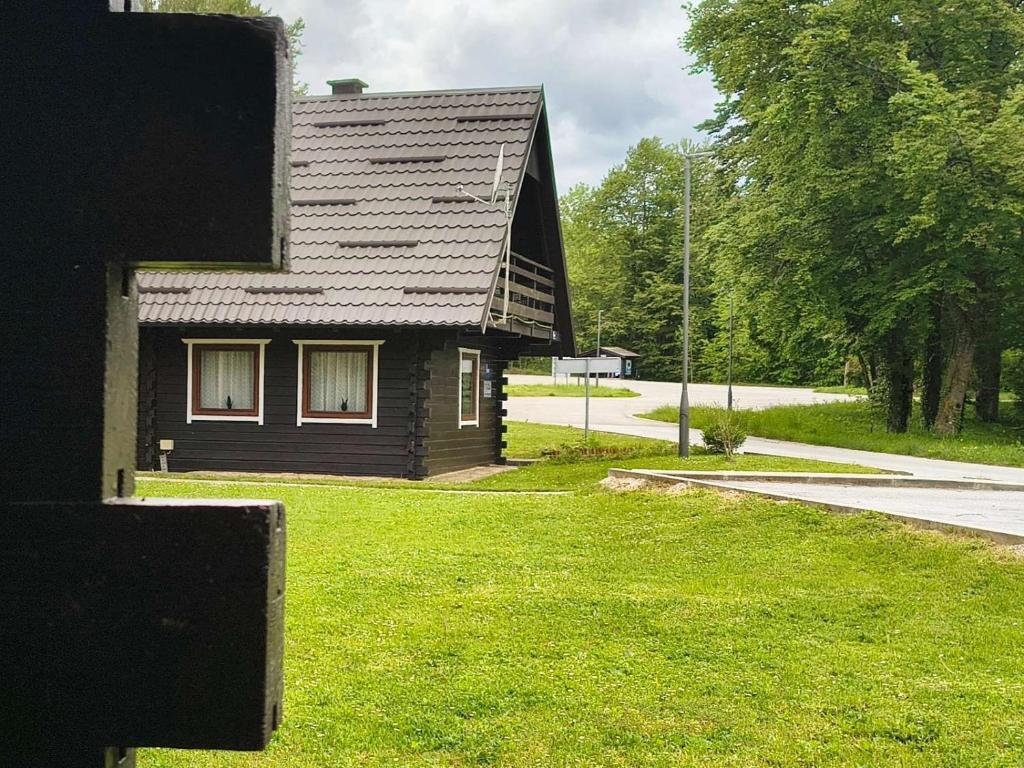 a black house with a grass yard next to a road at Edison,Plitvice Lakes in Jezerce