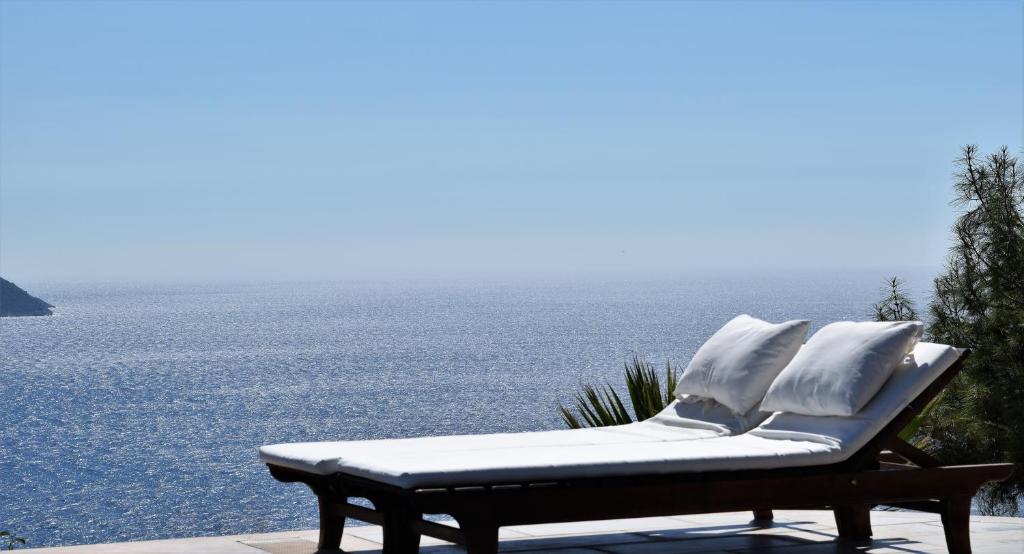 un banco sentado en un patio con vistas al agua en Kabak Avalon Bungalows, en Faralya