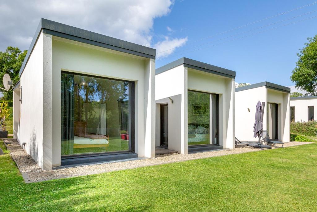 a house with large windows on a lawn at Sitelles Lodge Cube avec spa in Concarneau